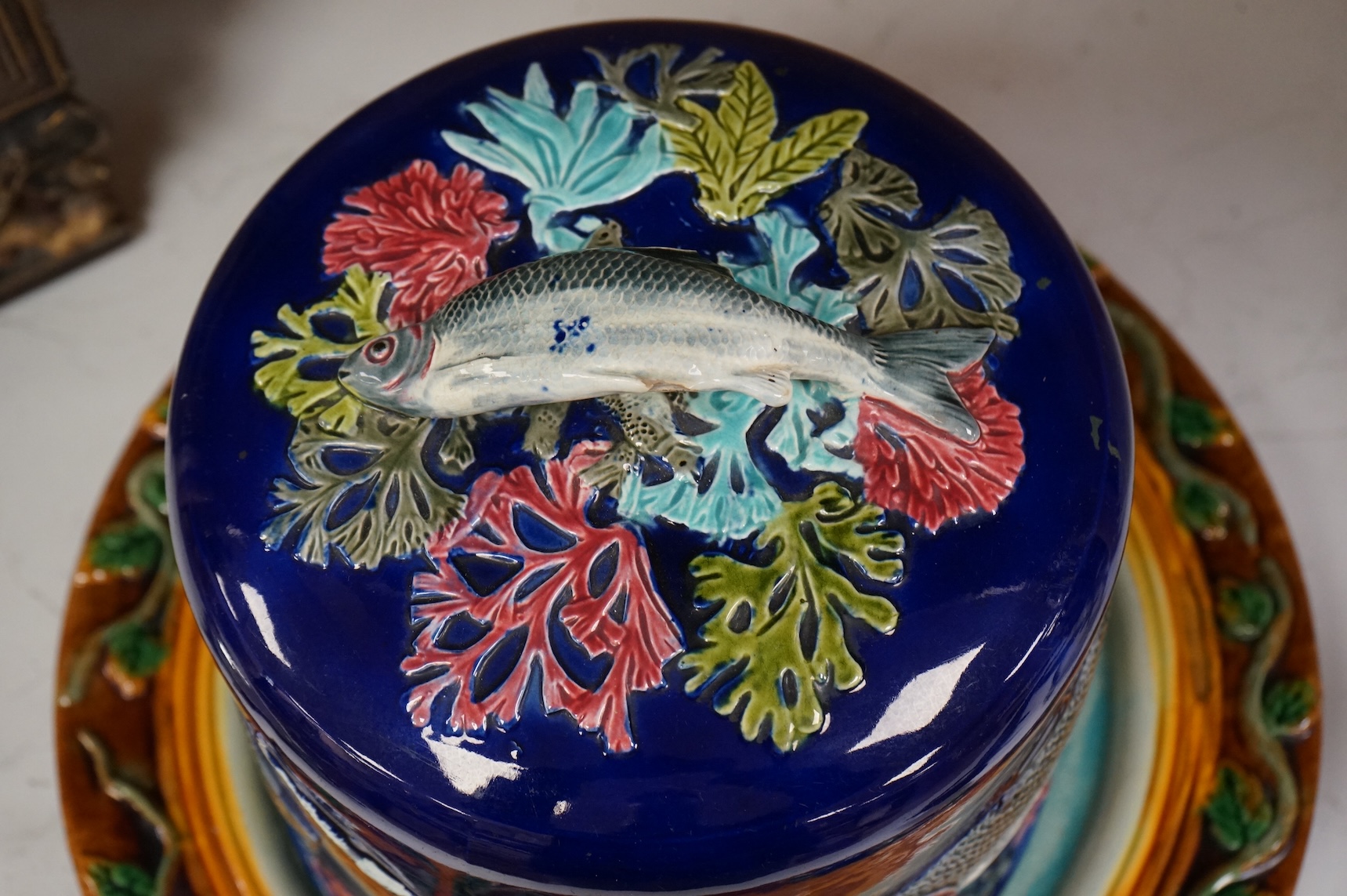 A Victorian majolica cheese dome decorated with fish and seaweed, and a later dish, dome 23cm high, 23cm diameter, dish 24cm internal diameter